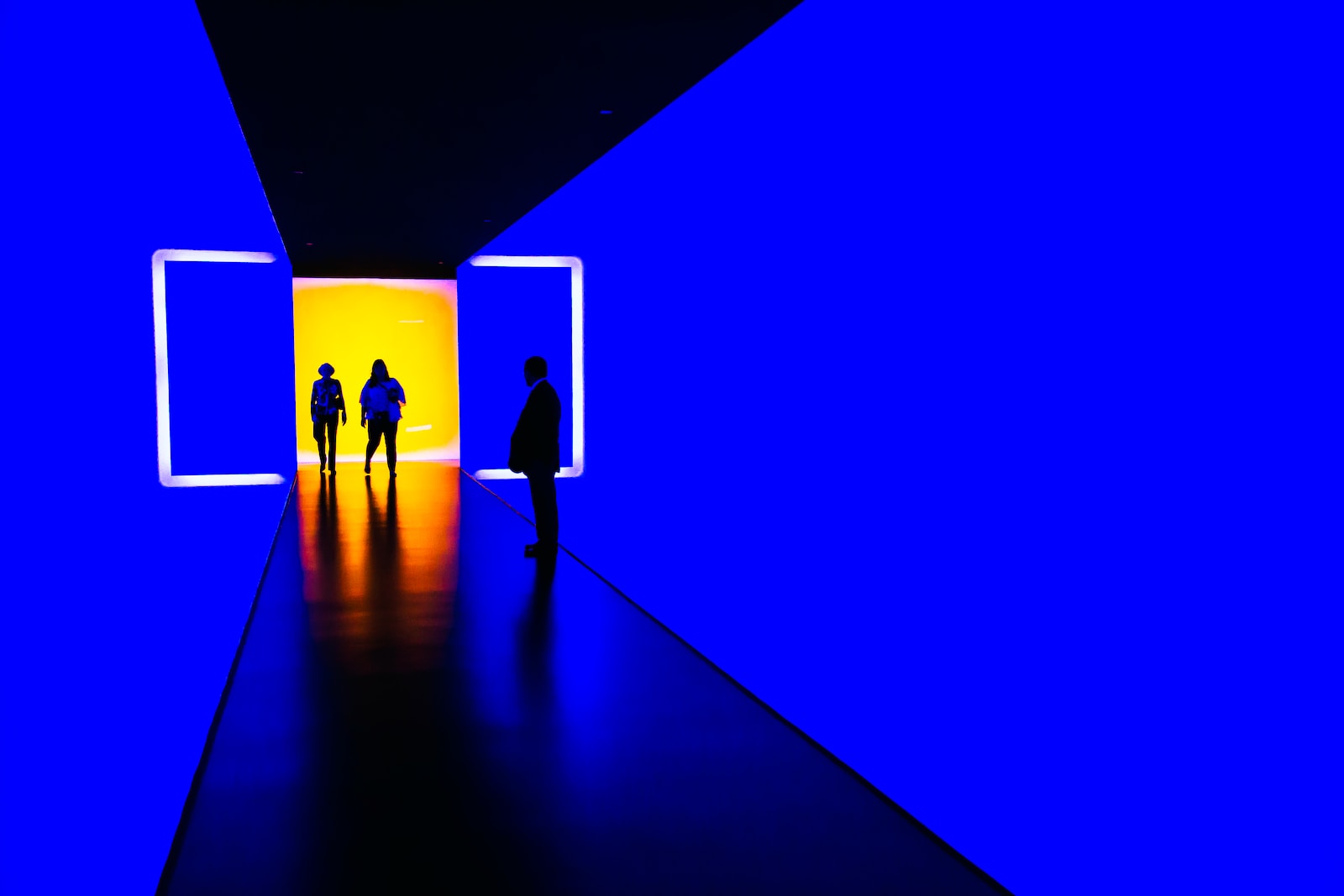 three person standing near wall inside building